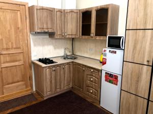 eine Küche mit Holzschränken und einem weißen Kühlschrank in der Unterkunft GIL apartments, Korzo 7,2 centre in Uschhorod