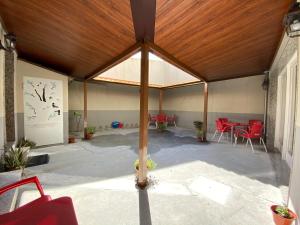 a large pavilion with red chairs and a wooden ceiling at Albergue Pereiro in Melide