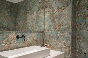 a bathroom with a sink and a tiled wall at PINACOTA SUITES ATHENS in Athens +116 photos