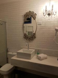 uma casa de banho com um lavatório, um espelho e um WC. em Suite Família Inconfidentes em Ouro Preto