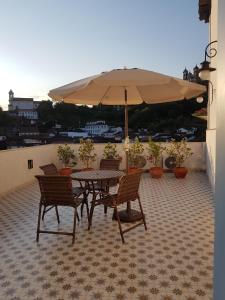 una mesa y sillas con una sombrilla en el balcón en Suite Família Inconfidentes en Ouro Preto