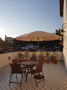 d'une table, de chaises et d'un parasol sur le balcon. dans l'établissement Suite Família Inconfidentes, à Ouro Preto