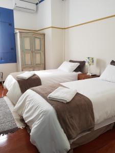 a bedroom with two beds with white sheets and brown blankets at Suite Família Inconfidentes in Ouro Preto