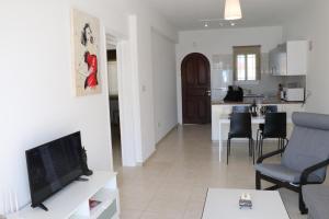 un soggiorno con TV e cucina di Cyking 2 bed Apartment with pool & 10 min to beach a Paphos