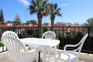 un tavolo bianco e sedie su un balcone con palme di Cyking 2 bed Apartment with pool & 10 min to beach a Paphos