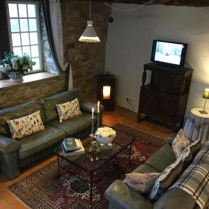 Una sala de estar con un sofá y un televisor. en Les Gîtes Pérard, en Caylus