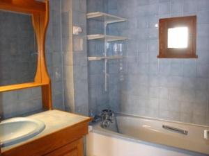 W łazience znajduje się umywalka, wanna i lustro. w obiekcie Magnimon 2 - Appartement rustique dans belle maison de village - Domaine Alpe d'Huez w mieście Villard-Reculas