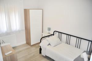 um quarto branco com uma cama e um espelho em Apartamento El Monasterio em Toledo