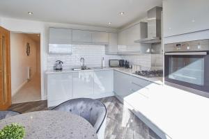 una cocina con electrodomésticos blancos, mesa y sillas en Host & Stay - The View, Hudsons Yard House, en Whitby