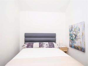 1 dormitorio con 1 cama blanca y una pintura en la pared en Apartment Sensa, en Trogir