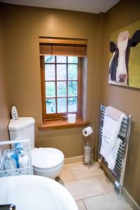 a bathroom with a toilet and a cow painting on the wall at Kirkstyle Hideaway in Arbroath