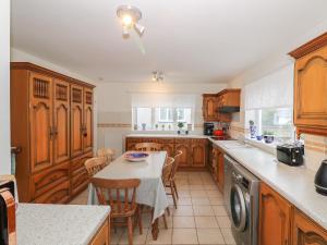 a kitchen with wooden cabinets and a table with chairs at Fernlea in Morfa Nefyn