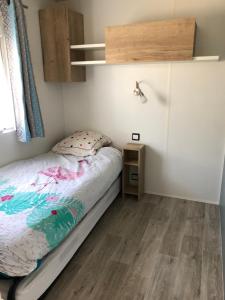 a small bedroom with a bed and a wooden floor at Mobile Home - Les Dunes de Contis in Saint-Julien-en-Born