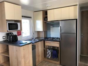 a kitchen with a stainless steel refrigerator and cabinets at Mobile Home - Les Dunes de Contis in Saint-Julien-en-Born