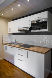 a kitchen with white cabinets and a sink and a microwave at Le Refuge in Lamoura