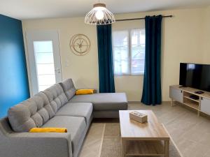a living room with a couch and a tv at Gîte Hibiscus in Seigy