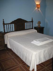 ein Schlafzimmer mit einem Bett mit weißer Bettwäsche und einer Lampe in der Unterkunft Cortijo El Rey in El Almicerán