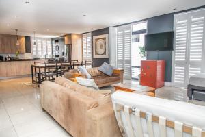 a living room with two couches and a kitchen at Modern Beachfront 2 Bed Apartment 144 Eden on the Bay, Blouberg, Cape Town in Bloubergstrand