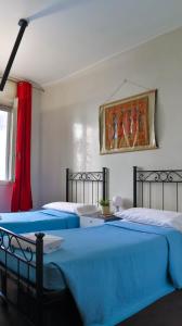 two blue beds in a bedroom with a painting on the wall at I Am Here - Gioia66 in Milan