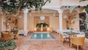 a swimming pool in a room with tables and chairs at Riad l'Oiseau du Paradis in Marrakech