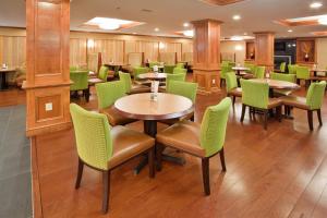 a restaurant with tables and green chairs at Holiday Inn Express Hotel & Suites Fredericksburg, an IHG Hotel in Fredericksburg