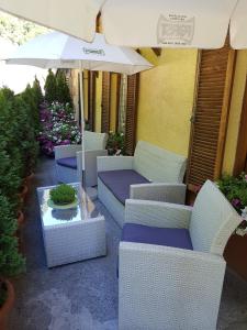 eine Terrasse mit weißen Korbstühlen und einem Sonnenschirm in der Unterkunft Gasthof Neuratheis in Schnals
