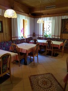 een eetkamer met tafels, stoelen en ramen bij Gasthof Neuratheis in Senales