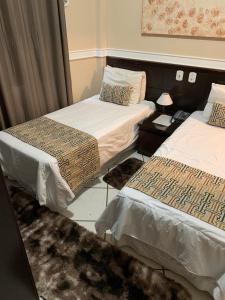 um quarto com duas camas e uma mesa com um candeeiro em Hanna Palace Hotel em Barra do Piraí