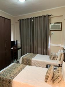 a hotel room with two beds and a desk at Hanna Palace Hotel in Barra do Piraí