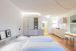 a white bedroom with two beds and a table at Hus Appartement - Nr. 1 in Valdaora