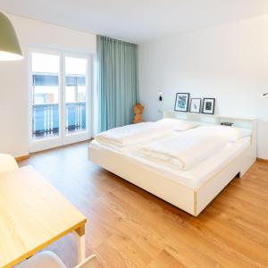 a large white bedroom with a large bed and a table at Hus Appartement - Nr. 1 in Valdaora