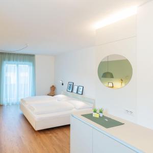 Habitación blanca con cama y espejo en Hus Appartement - Nr. 1 en Valdaora