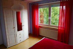 um quarto com cortinas vermelhas e uma grande janela em Ferienwohnung Tielmann em Felsberg