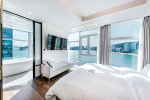 sypialnia z dużym białym łóżkiem i dużymi oknami w obiekcie H Avenue Gwanganri Beach w Pusanie