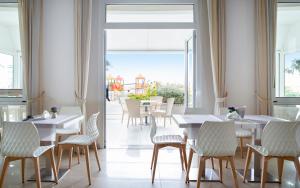 un ristorante con tavoli e sedie bianchi e una grande finestra di Hotel Riviera a Bellaria-Igea Marina