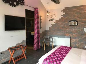 une chambre avec un lit et un mur de briques dans l'établissement Le Manoir d'à Côté, à Courseulles-sur-Mer