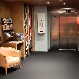 a room with a stainless steel refrigerator and a chair at ibis Arles in Arles