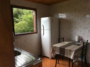 une cuisine avec une table et un réfrigérateur blanc dans l'établissement Casa Sossego da Montanha, à Visconde de Mauá