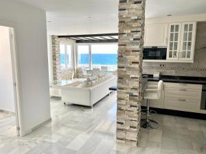 a white kitchen with a stone pillar in the middle at Luxury Puerto Banus Penthouse With Parking & WI-FI in Marbella