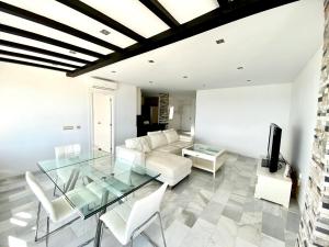 a living room with a glass table and white furniture at Luxury Puerto Banus Penthouse With Parking & WI-FI in Marbella