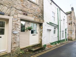 an old stone building with white doors on a street at Lottie's Loft in Grassington