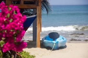 um barco azul sentado na praia com flores rosas em Baja Canoas Hotel em Canoas de Punta Sal