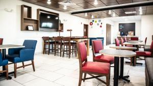 a restaurant with tables and chairs and a bar at Holiday Inn Express Hotel & Suites Sedalia by IHG in Sedalia