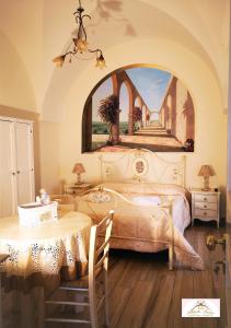 a bedroom with a bed with a table and a painting at Archetto Bianco in Martina Franca