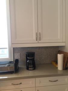 a kitchen counter with white cabinets and a coffee maker at Comfortable private space in Pickering