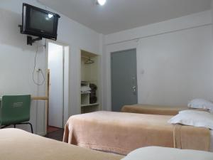a room with two beds and a tv on the wall at City Hotel in Caxias do Sul