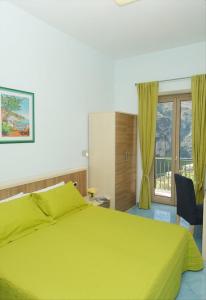 a bedroom with a yellow bed and a window at Dint'a Torre Bed and Breakfast in Scala
