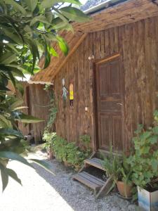 un cobertizo de madera con puerta y algunas plantas en Olympos Yakamoz Pansiyon, en Olympos
