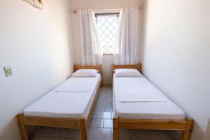 two beds in a room with a window at OYO Day Hostel in Cuiabá