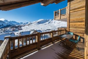 uma varanda com uma mesa e vista para as montanhas cobertas de neve em ODYSSEE B201 - Magnifique Duplex sur les pistes em La Toussuire